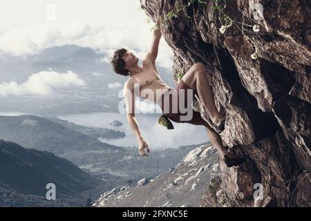 Jeune homme professionnel rock grimpeur pratiquant en montagne sur fond ciel nuageux. Collage, illustrations Banque D'Images