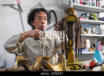 (210527) -- XILINHOT, 27 mai 2021 (Xinhua) -- Xilinhu fait un artisanat en forme de selle à son atelier de Xilinhot, dans la région autonome de la Mongolie intérieure de la Chine du nord, le 26 mai 2021. L'équitation, le tir à l'arc et la lutte sont appelés les trois compétences des hommes du groupe ethnique mongol. Depuis 2005, le handicapeur Xilinhu du groupe ethnique mongol a impliqué les symboles culturels de selle, d'arc et de flèche et de costume de lutte dans la fabrication de l'artisanat pour promouvoir la culture traditionnelle du groupe ethnique. (Xinhua/Peng Yuan) Banque D'Images