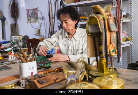 (210527) -- XILINHOT, 27 mai 2021 (Xinhua) -- Xilinhu fait un artisanat à son atelier de Xilinhot, dans la région autonome de la Mongolie intérieure, au nord de la Chine, le 26 mai 2021. L'équitation, le tir à l'arc et la lutte sont appelés les trois compétences des hommes du groupe ethnique mongol. Depuis 2005, le handicapeur Xilinhu du groupe ethnique mongol a impliqué les symboles culturels de selle, d'arc et de flèche et de costume de lutte dans la fabrication de l'artisanat pour promouvoir la culture traditionnelle du groupe ethnique. (Xinhua/Peng Yuan) Banque D'Images