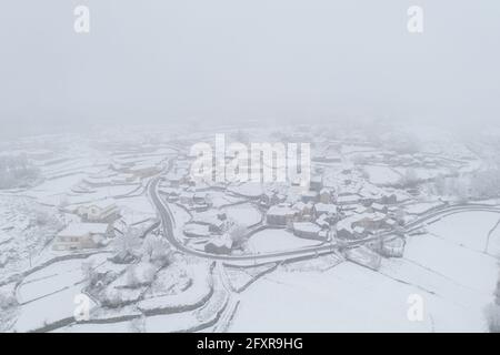 Vue aérienne par drone d'une route et d'un village isolé couvert de neige à Vila Real, Norte, Portugal, Europe Banque D'Images