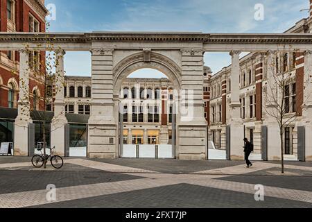 Personne passant devant l'entrée du Victoria and Albert Museum, Londres, Kensington, Angleterre, Royaume-Uni, avec les dégâts causés par la bombe conservés dans les murs Banque D'Images