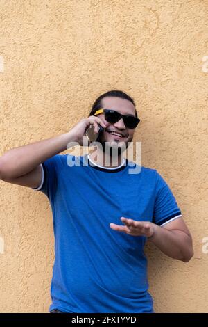 jeune homme latino souriant lors d'un appel téléphonique. Tir vertical. La vie latine en amérique Banque D'Images