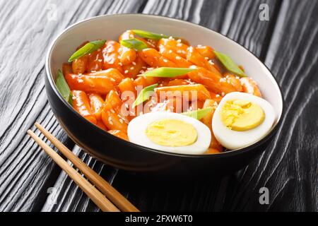 Tteokbokki dukbokki est une cuisine populaire coréenne faite de gâteaux de riz doux et bien cuits dans une sauce sucrée et épicée dans un bol sur la table. Banque D'Images