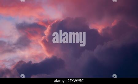 Magenta et bleu contrastant des paysages de nuages intenses et éclatants avec des nuages illuminés dans différentes nuances contre des couchers de soleil éclatants. Banque D'Images