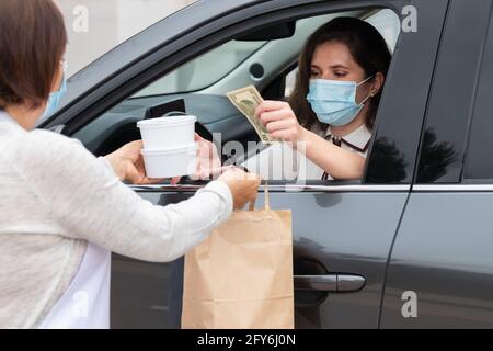 Femme d'affaires en voiture achetant des plats à emporter et payant il Banque D'Images