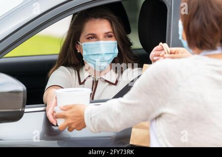 Femme dans une voiture livrée à emporter et un sac en papier: Sélectif foyer. Concept de sécurité. Banque D'Images