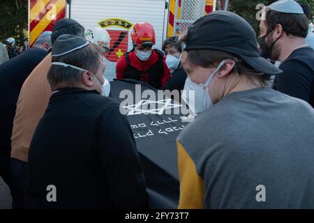 Curitiba, Brésil. 27 mai 2021. Les gens portant des couvertures de bouche à nez portent le cercueil contenant les restes de l'architecte brésilien Jaime Lerner, qui est décédé dans la nuit du 27 mai 2021, à l'âge de 83 ans. Lerner est considéré comme le père de la « ville verte » Curitiba, qui a reçu le « Globe Sustainable City Award » en Suède en 2010. Credit: Cassiano Rosario/dpa/Alay Live News Banque D'Images