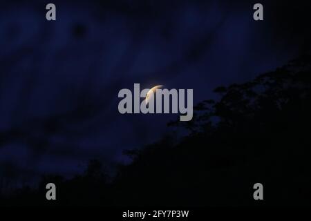 L'ombre de la terre tombe en partie sur une pleine lune alors qu'elle s'élève au-dessus d'un flanc de montagne pendant une éclipse lunaire totale vue d'Anilao dans la province de Batangas, au sud de Manille, Philippines. Banque D'Images