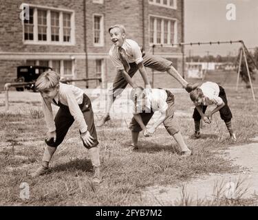 ANNÉES 1930 QUATRE GARÇONS ÉNERGIQUES RIANT DANS KNICCURBOCKERS CHEMISES BLANCHES CRAVATES JOUER À LEAPFROG SUR LE TERRAIN DE JEU DE L'ÉCOLE PRIMAIRE - B12008 HAR001 HARS CULOTTE JOIE STYLE DE VIE SANTÉ ATHLÉTISME COPIER ESPACE AMITIÉ PLEINE LONGUEUR PHYSIQUE FORME PHYSIQUE HOMMES CONFIANCE ATHLÉTIQUE B&W DOS OBJECTIFS ÉCOLES ACTIVITÉ GRADE BONHEUR PHYSIQUE LOISIR FORCE PANTALON EXTÉRIEUR RENFONCEMENT LOISIRS CHEMISES DIRECTION CRAVATES SUR LA CONNEXION PRIMAIRE ATHLÈTES FLÉCHIS FLEXIBILITÉ MUSCLES DE LEAPFROG ÉLÉGANT SOUTIEN CRAVATES PANTALON COURT KNICCURBOCKERS COOPÉRATION ÉCOLE DE CLASSE ÉNERGÉTIQUE JEUNES AVANT L'ADOLESCENCE AVANT L'ADOLESCENCE GARÇON TOGETHESTHNESS Banque D'Images