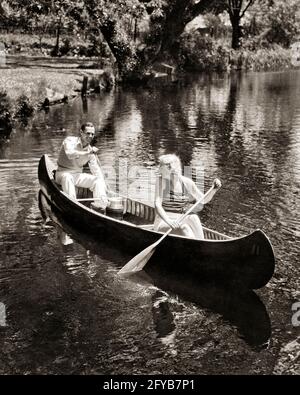 UN COUPLE DES ANNÉES 1930 ET UNE FEMME PAGAYANT UN CANOË EN COURS UN PIQUE-NIQUE D'ÉTÉ AVEC PANIER ET THERMOS - C1605 HAR001 HARS FITNESS AVIRON BLOND SANTÉ JEUNE ADULTE TRAVAIL D'ÉQUIPE CANOË HEUREUX JOIE STYLE DE VIE FEMMES MARIÉ RURAL CONJOINT MARI COPIER ESPACE AMITIÉ DEMI-LONGUEUR DAMES PERSONNES RUISSEAU MÂLES TRANSPORT B&W PARTENAIRE ÉTÉ CANOË ACTIVITÉ PHYSIQUE GAI GRAND ANGLE AVENTURE FORCE ET EXCITATION LOISIRS THERMOS OAR SOURIT AL FRESCO PAGAIES FLEXIBILITÉ MUSCLES JOYEUX PIQUE-NIQUE COOPÉRATION ÉLÉGANTE SAISON DE PAGAYAGE TOGETHERNESS FEMMES JEUNE ADULTE HOMME NOIR ET BLANC Banque D'Images