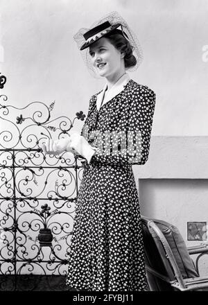 FEMME BRUNETTE CHIC ET TENDANCE DES ANNÉES 1940 PORTANT UNE ROBE À IMPRIMÉ AVEC GANTS À COL BLANC ET CHAPEAU PERKY AVEC VOILE EN FILET - G1027 HAR001 HARS DEMI-LONGUEUR FEMMES PERSONNES PRENANT SOIN DE LA CONFIANCE DU VOILE B&W PORTE BRUNETTE STYLES DE BIEN-ÊTRE ET FIERTÉ DE FER FORGÉ PERKY CONCEPTUEL ATTACHÉ ÉLÉGANT DÉCORATIF MODE MINCE JEUNE FEMME ADULTE NOIR ET L'ETHNIE BLANCHE CAUCASIENNE HAR001 ANCIEN MODE Banque D'Images