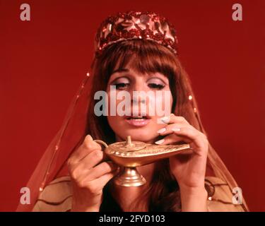 ANNÉES 1960, JEUNE FEMME DES ANNÉES 1970 EN COSTUME DE GÉNIE FROTTANT LA LAMPE MAGIQUE - KG3005 HAR001 HARS MAGIQUE AMUSANT EXCENTRIQUE JEUNES ADULTES JEUNE FEMME ADULTE JEUNE RACE BLANCHE ERRATIQUE EXOTIQUE HAR001 VIEUX À LA MODE Banque D'Images