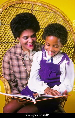 LES ANNÉES 80 SOURIANT DE LA MÈRE AFRO-AMÉRICAINE ET DE LA FILLE AFRO COIFFURE ASSIS DANS CHAISE EN ROTIN À HAUT DOSSIER LISANT UN LIVRE - KJ11213 TRA001 HARS MÈRES VIEUX TEMPS FUTUR NOSTALGIE VIEILLE MODE 1 STYLE JUVÉNILE COMMUNICATION TRAVAIL D'ÉQUIPE INFORMATION STYLE DE VIE SATISFACTION CÉLÉBRATION FEMMES SANTÉ ACCUEIL VIE DEMI-LONGUEUR FEMMES FILLES PERSONNES AFRO OBJECTIFS DE SOINS SUCCÈS ROTIN BONHEUR BIEN-ÊTRE AFRO-AMÉRICAINS AFRO-AMÉRICAIN ET CHOIX EXCITATION COIFFURE PROGRÈS LOISIRS NOIR ETHNICITÉ FIERTÉ OPPORTUNITÉ AUTORITÉ CONCEPTUELLE IMAGINATION SOUTIEN ÉLÉGANT DES IDÉES DE CROISSANCE JEUNES SOUTENUES Banque D'Images