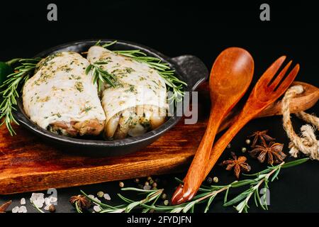 Viande pour le gril et le barbecue.cuisses de poulet crues sur fond sombre.cuisses de poulet crues en marinade blanche avec épices de romarin frais. Banque D'Images