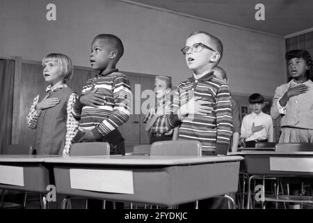 LES ENFANTS DE L'ÉCOLE DES ANNÉES 1960 DEBOUT À DES BUREAUX DISANT PROMESSE DE ALLÉGEANCE AU DRAPEAU DES ÉTATS-UNIS AVEC LES MAINS SUR LEUR COEUR - S15673 HAR001 HARS DEMI-LONGUEUR INSPIRATION ÉTATS-UNIS D'AMÉRIQUE HOMMES SIX BUREAUX B&W ÉCOLES NORD-AMÉRICAINES FREEDOM GRADE COEURS AFRO-AMÉRICAINS AFRO-AMÉRICAINS BAS ANGLE NOIR FIERTÉ INTÉGRÉE PATRIOT PATRIOTE PRIMAIRE PATRIOTE DIVERS COOPÉRATION SCOLAIRE DE CROISSANCE JUVÉNILES UN SERMENT D'ALLÉGEANCE PATRIOTIQUE RÉCITANT L'APPARTENANCE ETHNIQUE BLANCHE ET NOIRE HAR001 AFRO-AMÉRICAINS À L'ANCIENNE Banque D'Images