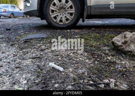 une seringue jetable usagée est posée sur le sol à proximité la voiture Banque D'Images