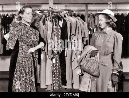 ANNÉES 1940 UNE VENDEUSE DU GRAND MAGASIN TRÈS UTILE TENANT UNE ROBE POUR LE CLIENT PORTER UN CHAPEAU AVEC UN MANTEAU ET UN SAC À MAIN AU-DESSUS DE SON BRAS - S7884 HAR001 HARS 1 STYLE DE COMMUNICATION JEUNE ADULTE DÉPARTEMENT ASSISTANT DE STYLE DE VIE COMMIS FEMMES PORTE-VÊTEMENTS EMPLOIS DE DÉTAIL COPIE DEMI-LONGUEUR FEMMES PERSONNES BOUTIQUES B&W SHOPPER ROBES SHOPPERS COMPÉTENCE MÉTIER VENDRE COMPÉTENCES SERVICE À LA CLIENTÈLE ET CHOIX PROFESSIONNELS MAGASINS VENDEUSES UTILES FEMMES DE VENTE COMMERCE ÉLÉGANT JEUNE FEMME ADULTE NOIR ET BLANC ENTREPRISES CAUCASIENNES ETHNICITÉ HAR001 À L'ANCIENNE Banque D'Images