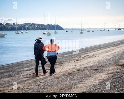 AUCKLAND, NOUVELLE-ZÉLANDE - 19 mai 2021 : deux femmes marchant le long de la plage de Bucklands. Auckland, Nouvelle-Zélande - 13 mai 2021 Banque D'Images