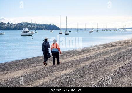 AUCKLAND, NOUVELLE-ZÉLANDE - 19 mai 2021 : deux femmes marchant le long de la plage de Bucklands. Auckland, Nouvelle-Zélande - 13 mai 2021 Banque D'Images