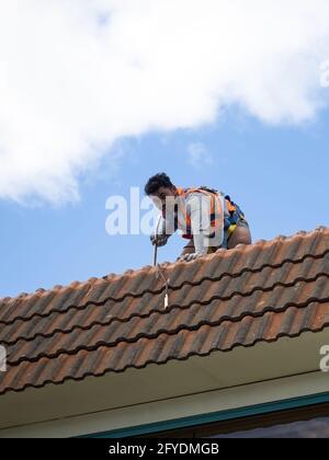 AUCKLAND, NOUVELLE-ZÉLANDE - 19 mai 2021 : Tradie travaille sur le toit de tuiles. Auckland, Nouvelle-Zélande - 13 mai 2021 Banque D'Images