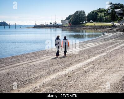 AUCKLAND, NOUVELLE-ZÉLANDE - 19 mai 2021 : deux femmes marchant le long de la plage de Bucklands. Auckland, Nouvelle-Zélande - 13 mai 2021 Banque D'Images