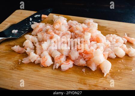 Crevettes cuites grossièrement hachées : crevettes pelées qui ont été grossièrement hachées sur une planche à découper en bambou Banque D'Images