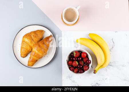 Petit-déjeuner plat avec café, croissants et baies pour le petit-déjeuner sur fond tricolore pastel. Vue de dessus, plan d'appartement Banque D'Images