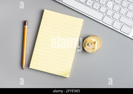 Bloc-notes et dogecoin en papier adhésif vierges sur une table grise. Vue de dessus. Banque D'Images