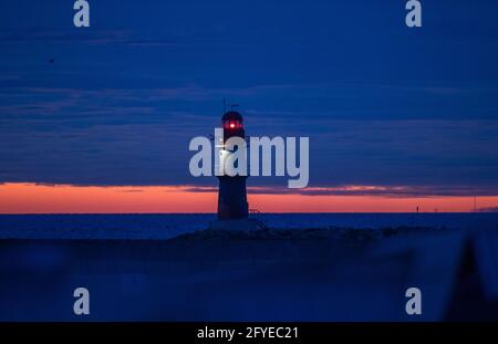 28 mai 2021, Mecklembourg-Poméranie occidentale, Warnemünde : le phare de la jetée sur la mer Baltique clignote avant le lever du soleil. Le Service météorologique allemand (DWD) présente son bilan météorologique pour le printemps. Photo: Jens Büttner/dpa-Zentralbild/dpa Banque D'Images