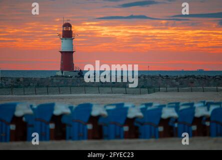 28 mai 2021, Mecklembourg-Poméranie occidentale, Warnemünde: Le soleil levant colore le ciel derrière le phare sur la jetée à la mer Baltique orange-rouge. Le Service météorologique allemand (DWD) présente son bilan météorologique pour le printemps. Photo: Jens Büttner/dpa-Zentralbild/dpa Banque D'Images