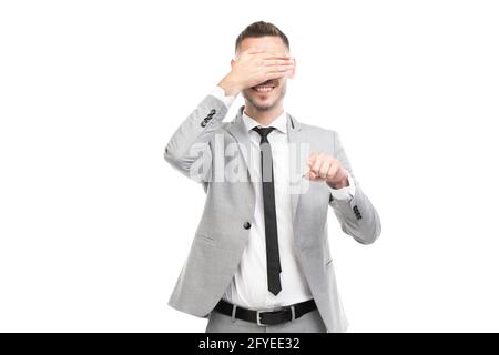 Portrait horizontal moyen d'un jeune homme caucasien, jeune adulte, portant une combinaison grise avec une cravate noire couvrant les yeux avec la main, fond blanc Banque D'Images