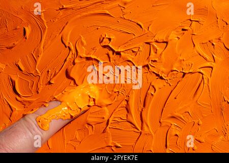 étalez une bande de couleur acrylique orange avec votre doigt Banque D'Images