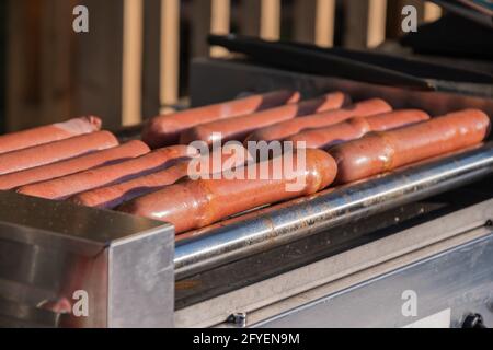 Les saucisses de hot dog sont frites sur une machine de cuisson rotative dans un café extérieur Banque D'Images