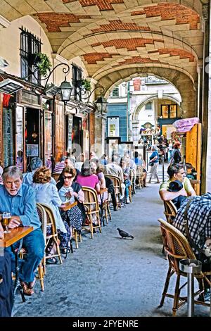 FRANCE. PARIS (75) PERSONNES SUR UNE TERRASSE CAFÉ-RESTAURANT, SOUS LES ARCHES, SUR LA PLACE DES VOSGES Banque D'Images