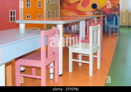 Un ensemble de jolies tables et chaises hautes pour enfants dans la salle de jeux de la maternelle. Banque D'Images