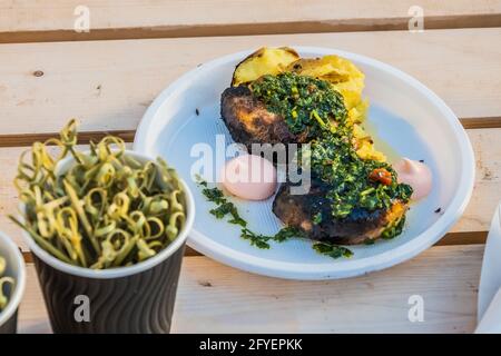 Cuisine végétarienne - tranches de pommes de terre chaudes recouvertes d'herbes et d'épices sur le comptoir d'un vendeur de rue. Fête gastronomique dans le parc de la ville. Rue fas Banque D'Images