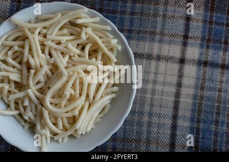 Pâtes cuites dans une assiette blanche sur fond à carreaux. Thème culinaire. Banque D'Images