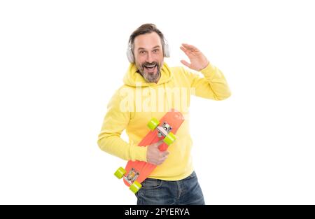 joyeux skateboarder écoutez de la musique dans les écouteurs tenez le skateboard isolé sur blanc, en s'amusant. Banque D'Images