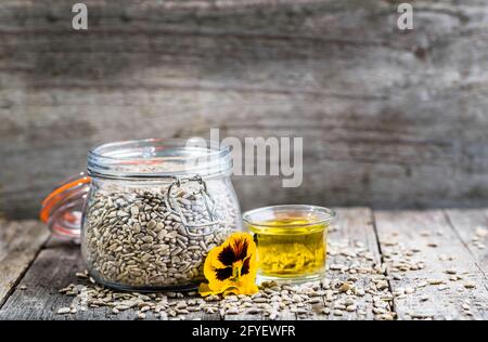 Huile de tournesol et graines de tournesol en pot sur table en bois Banque D'Images