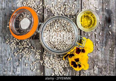 Verre d'huile de graines de tournesol dans un pot rustique sur une table en bois, plat posé par le dessus Banque D'Images