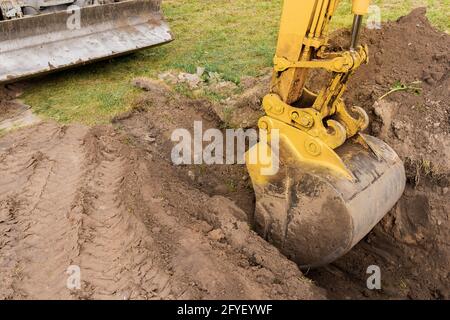 Un godet de pelle hydraulique avec une pile de terre creuse un trou sur le chantier de construction. Travail industriel. Banque D'Images