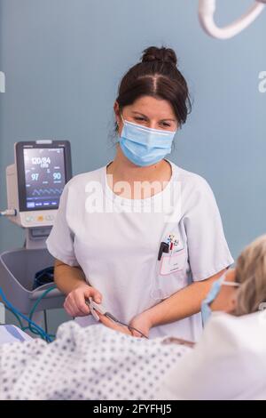 Infirmière avec un patient hospitalisé. Hôpital de Limoges, France, dosage de la saturation en oxygène-hémoglobine du sang avec un oxymètre de pouls. Banque D'Images