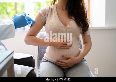 Médecin effectuant l'injection du vaccin Covid-19 à la femme enceinte patient Banque D'Images