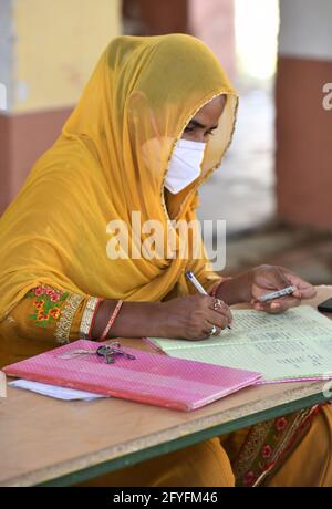 Beawar, Rajasthan, Inde, 27 mai 2021 : un agent de santé prend les détails personnels des résidents pour le vaccin COVID-19 sur le bureau d'enregistrement d'un centre de vaccination dans le village de Malpura près de Beawar. La vague prolongée et dévastatrice d'infections à Covid-19 en Inde a saisi les villes et a accablé les ressources sanitaires urbaines, mais elle a également atteint des profondeurs dans les zones rurales de l'Inde, où l'ampleur réelle de la dévastation est inconnue en raison de l'absence de tests étendus ou de données fiables. Crédit : Sumit Saraswat/Alay Live News Banque D'Images