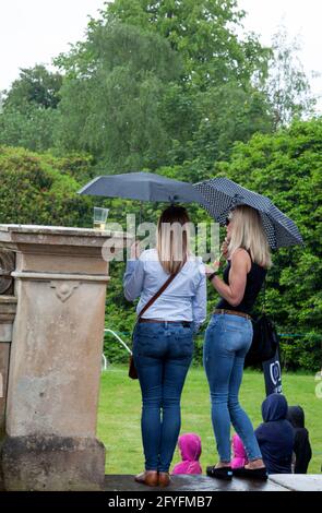 Deux spectateurs de dame avec parasols sous la pluie au Rhu Gala, Argyll, Écosse Banque D'Images