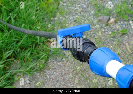 Un tuyau avec un robinet qui fournit de l'eau potable propre d'un puits profond dans la cour sur un fond flou d'herbe verte. Mise au point sélective. Banque D'Images