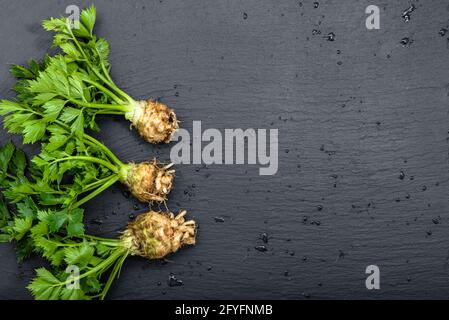 Racine de céleri avec feuilles sur fond noir, légumes du marché local, produits agricoles, espace de copie Banque D'Images