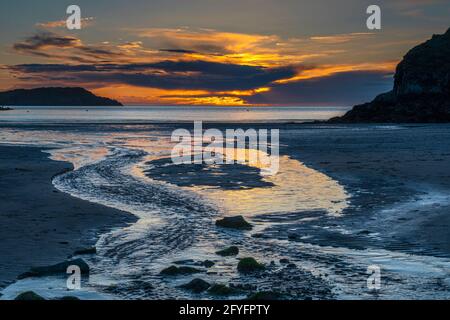 Cemaes Bay au coucher du soleil depuis Great Beach, Traeth Mawr, Anglesey, pays de Galles. Banque D'Images