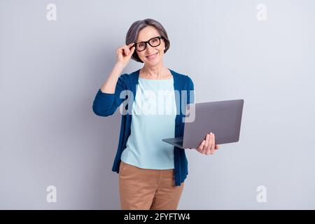 Portrait photo d'une femme d'affaires senior portant des lunettes à l'aide d'un ordinateur portable sourire isolé sur fond gris Banque D'Images