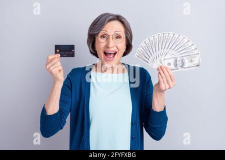 Photo portrait d'une femme d'affaires stupéfait montrant la carte de crédit billets de banque en dollars isolés sur fond gris Banque D'Images